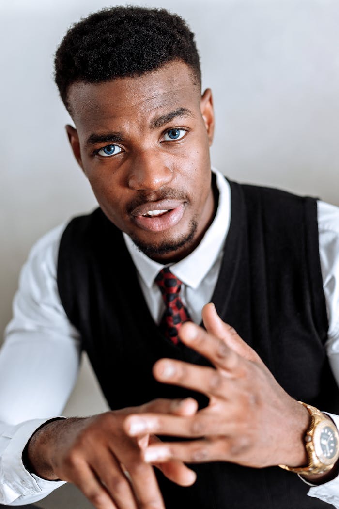 about-us Portrait of an African American man in formal attire gesturing with confidence indoors.